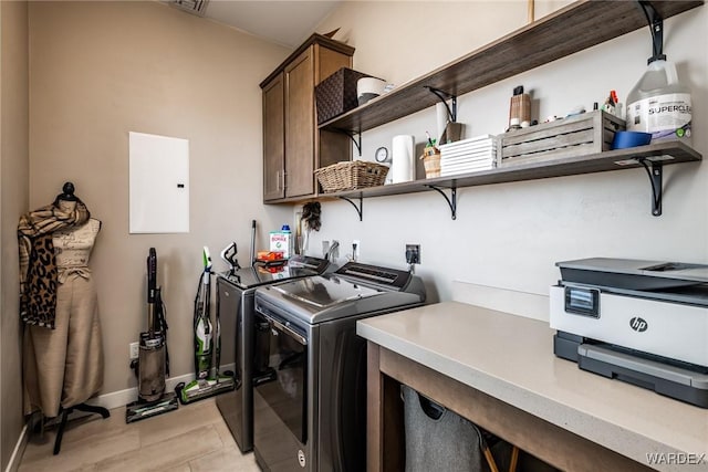 clothes washing area featuring baseboards, cabinet space, independent washer and dryer, and electric panel