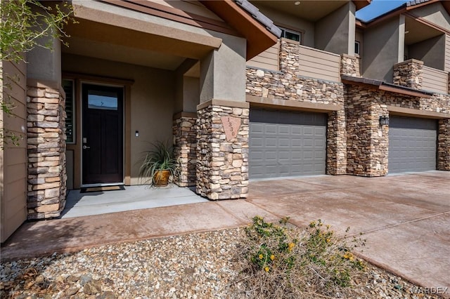property entrance featuring an attached garage, stucco siding, concrete driveway, and stone siding