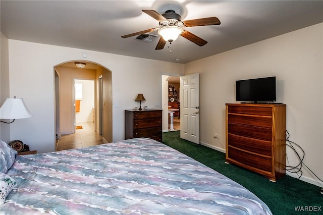 bedroom with arched walkways, a ceiling fan, visible vents, baseboards, and dark carpet