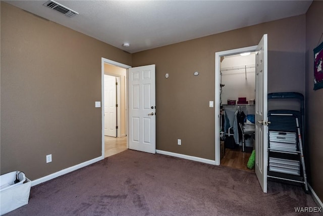 bedroom with visible vents, baseboards, a closet, carpet, and a walk in closet