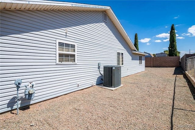 view of side of property with a fenced backyard and central AC