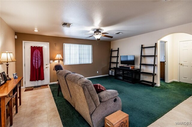 living room with arched walkways, visible vents, carpet flooring, ceiling fan, and baseboards