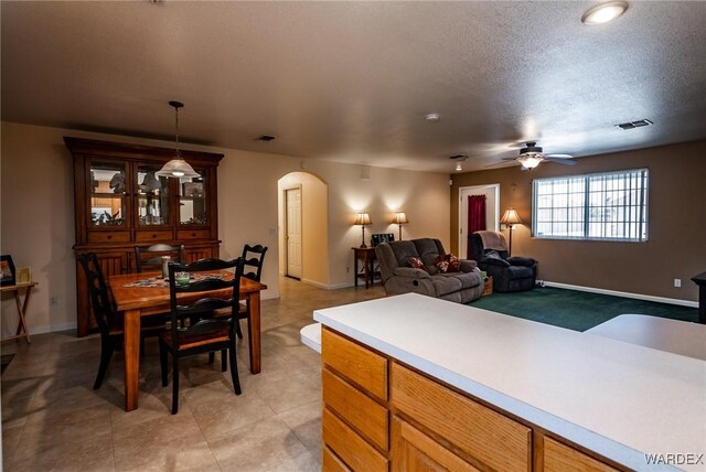 kitchen with arched walkways, pendant lighting, light countertops, open floor plan, and baseboards