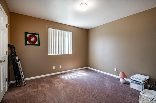 empty room featuring dark colored carpet and baseboards