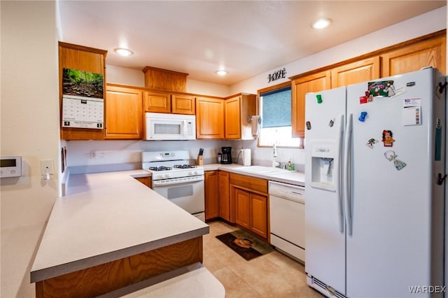 kitchen with brown cabinets, white appliances, light countertops, and a sink