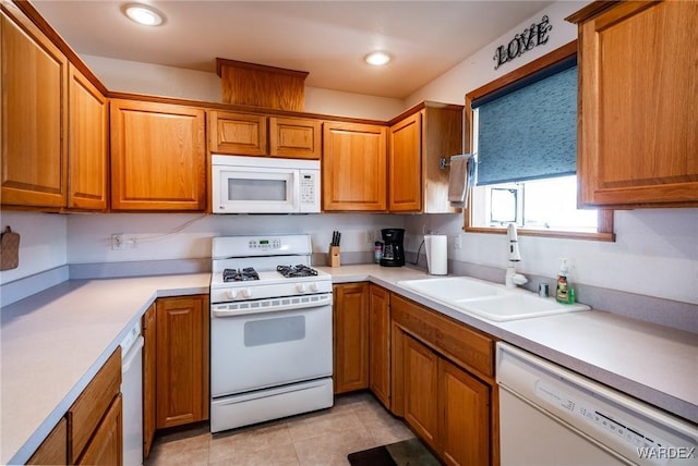 kitchen featuring light countertops, white appliances, a sink, and brown cabinets