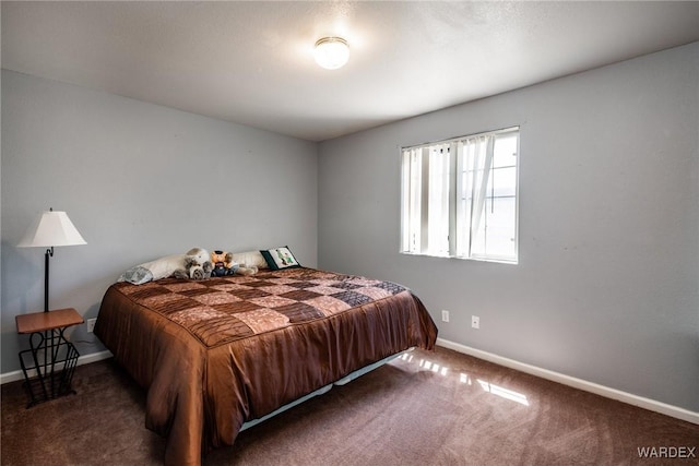 bedroom with dark carpet and baseboards