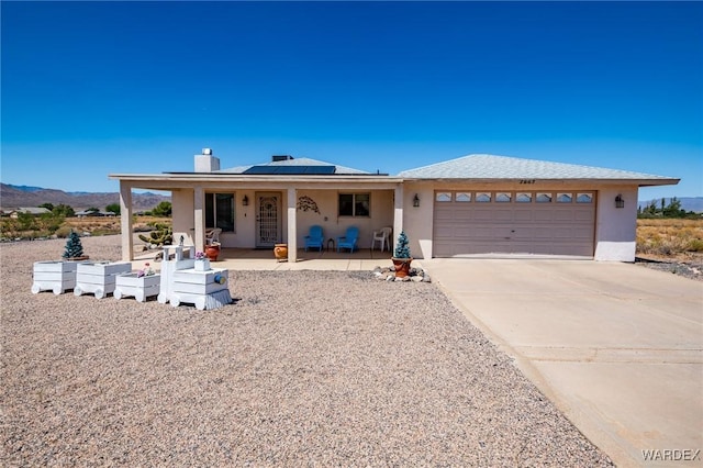 view of front of property with stucco siding, a porch, solar panels, concrete driveway, and a garage