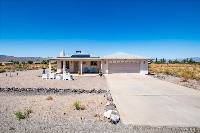 view of front of home featuring solar panels, a porch, an attached garage, a mountain view, and driveway