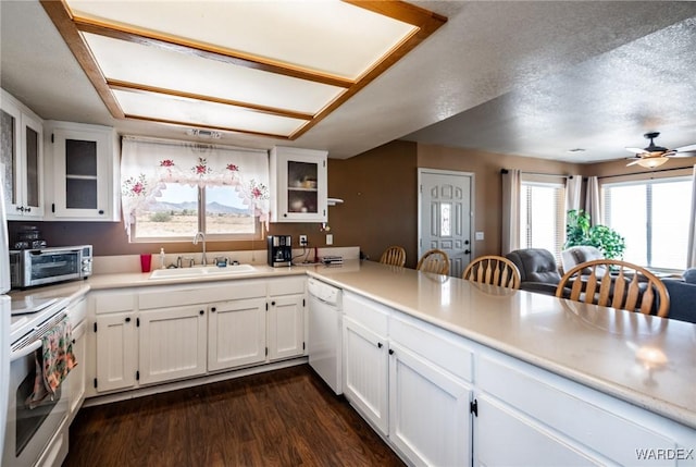 kitchen with white appliances, glass insert cabinets, light countertops, white cabinetry, and a sink