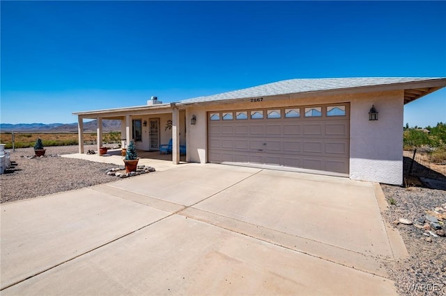 view of front facade with an attached garage, covered porch, driveway, and stucco siding