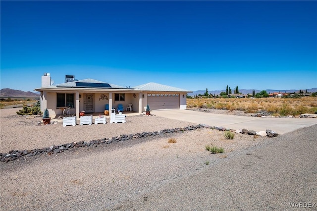 view of front of home with a chimney, concrete driveway, covered porch, an attached garage, and a mountain view