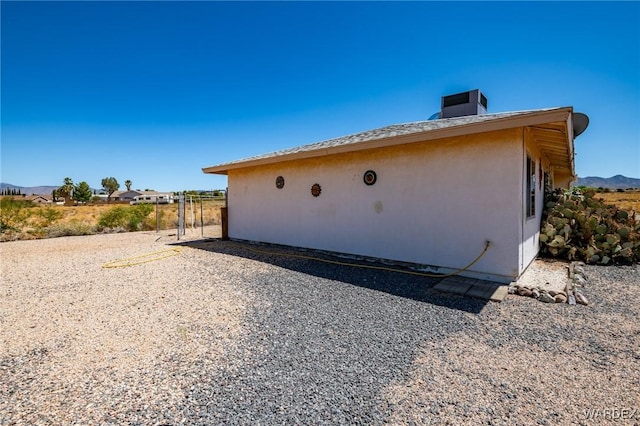 view of home's exterior with a mountain view, cooling unit, and stucco siding