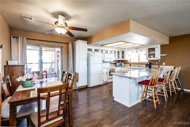 kitchen featuring light countertops, glass insert cabinets, white cabinets, white appliances, and a peninsula