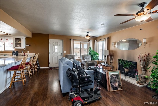 living area with a textured ceiling, dark wood-style flooring, and baseboards