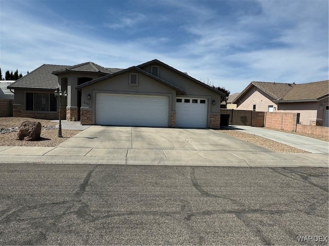 view of front of property with stucco siding, stone siding, fence, a garage, and concrete driveway