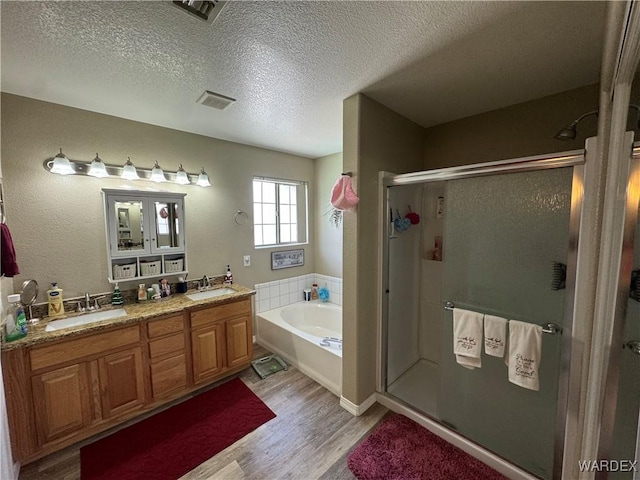 bathroom featuring a sink, a shower stall, wood finished floors, and a garden tub