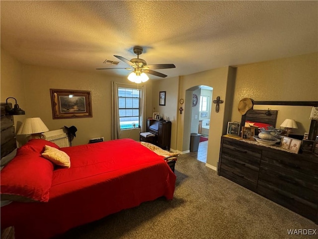 bedroom featuring a textured wall, a textured ceiling, visible vents, arched walkways, and carpet