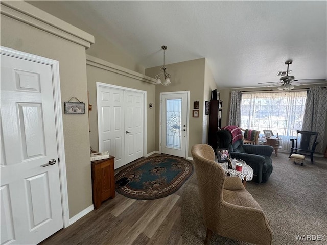 entrance foyer featuring ceiling fan with notable chandelier, baseboards, vaulted ceiling, and dark wood-style floors
