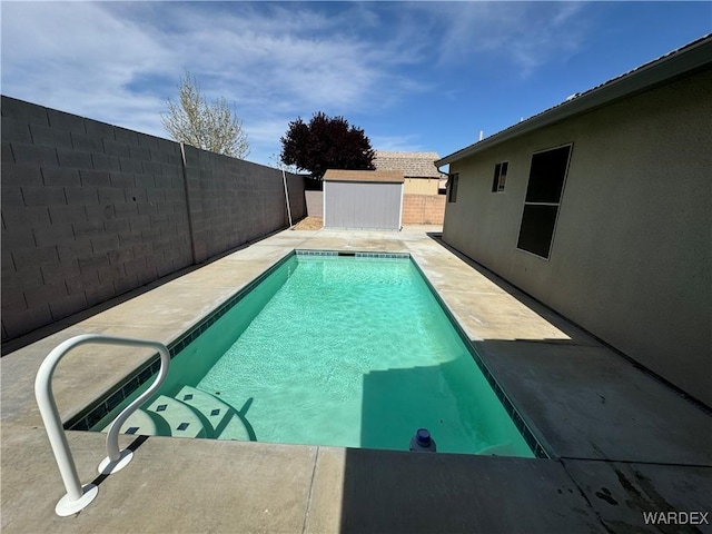 view of swimming pool featuring a fenced in pool, a patio, an outdoor structure, a fenced backyard, and a storage unit