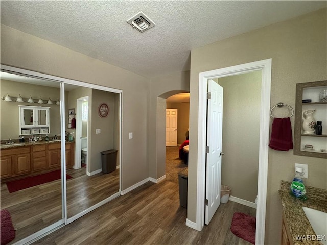 bathroom featuring a textured ceiling, vanity, visible vents, toilet, and wood finished floors