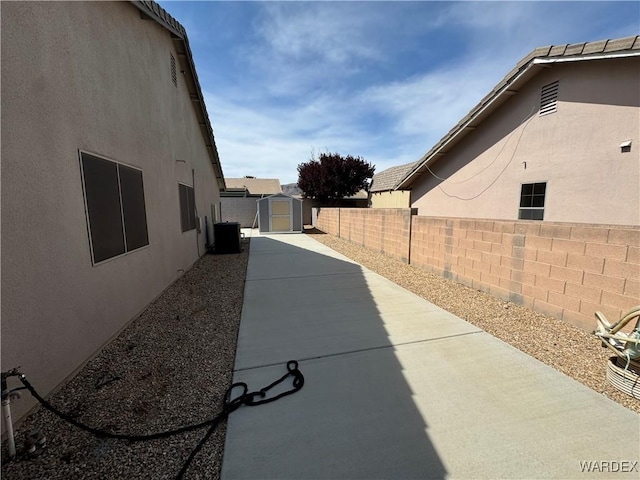 exterior space with a storage shed, an outbuilding, a fenced backyard, and central air condition unit