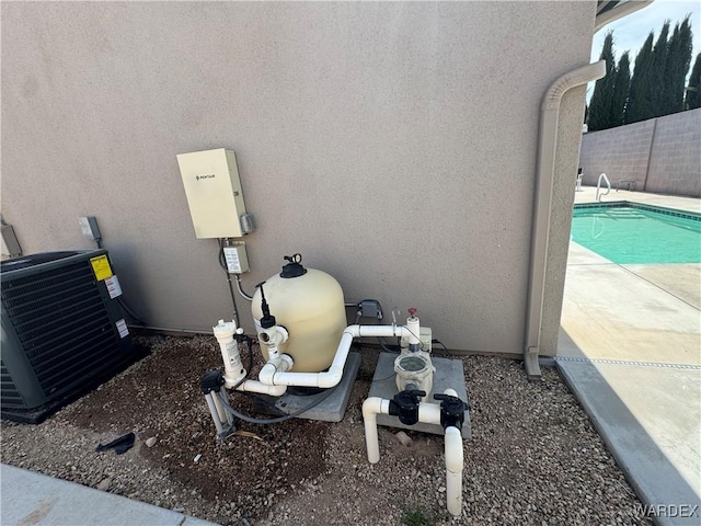 exterior details featuring central AC unit, a pool, fence, pump, and stucco siding