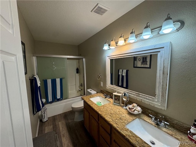 bathroom featuring toilet, wood finished floors, a sink, and visible vents