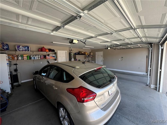 garage featuring water heater, baseboards, and a garage door opener