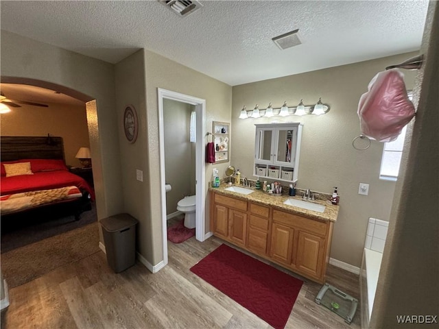 full bathroom with wood finished floors, a sink, and visible vents