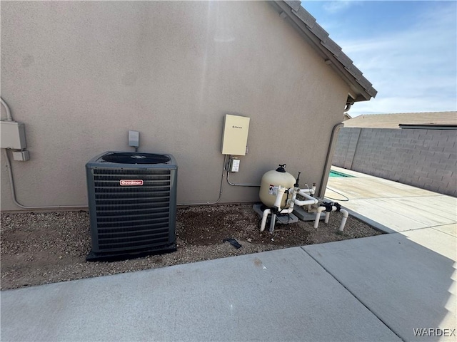 exterior details with fence, central AC unit, stucco siding, and pump