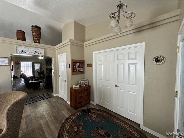 entryway with a chandelier, baseboards, a textured ceiling, and wood finished floors