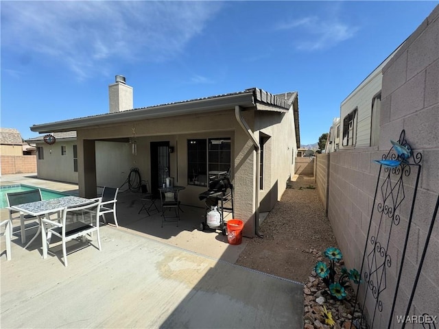 back of property featuring a chimney, a fenced backyard, a patio, stucco siding, and a fenced in pool
