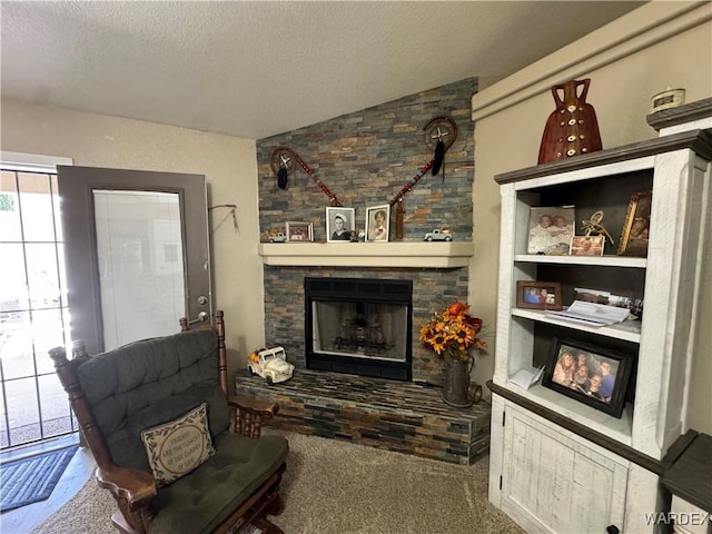 carpeted living room with a textured ceiling, vaulted ceiling, and a stone fireplace