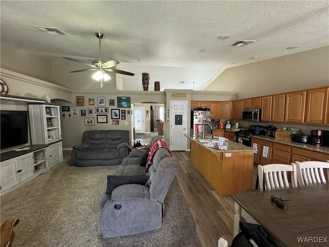 living area featuring dark wood-style flooring, visible vents, a ceiling fan, and vaulted ceiling
