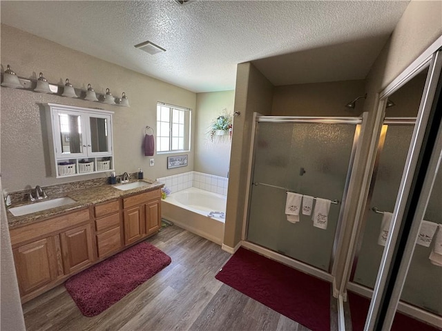 2121 Dale Evans Way, Kingman, AZ 86409 - bathroom with a shower stall, a bath, a textured ceiling, wood finished floors, and double vanity