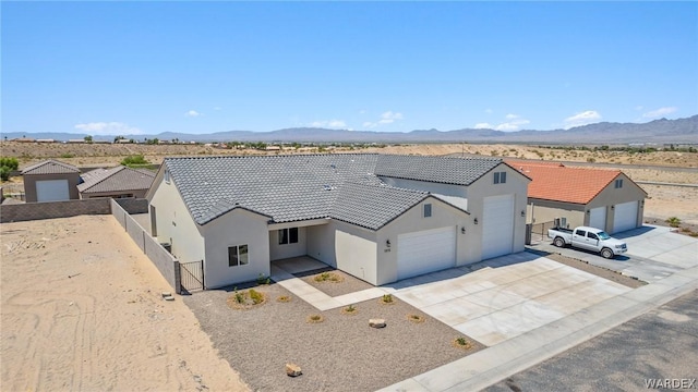 view of front of property featuring a mountain view, a garage, a tile roof, concrete driveway, and stucco siding