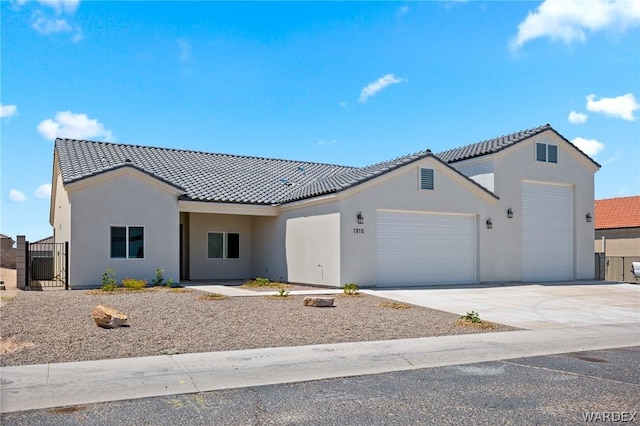 view of front of house featuring a garage, driveway, a tiled roof, and stucco siding