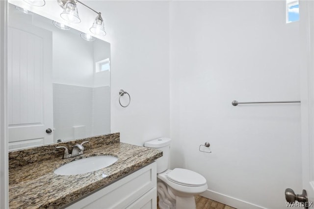 bathroom with wood finished floors, vanity, toilet, and a healthy amount of sunlight