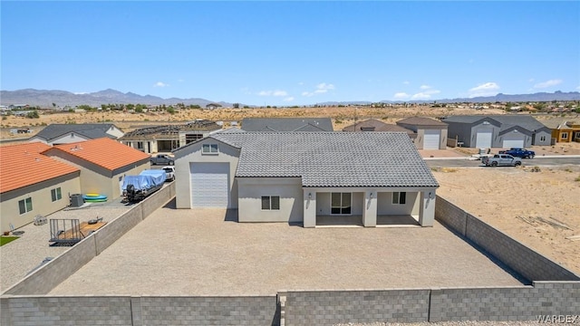 view of front of property featuring a fenced backyard, a residential view, a tiled roof, a mountain view, and stucco siding