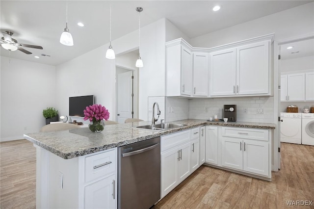 kitchen featuring decorative light fixtures, washing machine and clothes dryer, stainless steel dishwasher, white cabinetry, and a sink