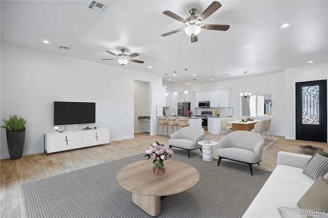 living room with baseboards, light wood-style flooring, visible vents, and recessed lighting