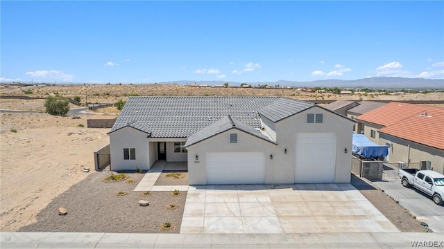 view of front of home featuring a tiled roof, an attached garage, a mountain view, and stucco siding