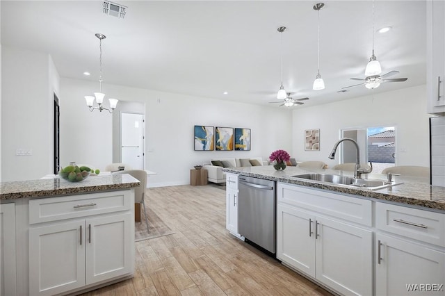 kitchen featuring visible vents, hanging light fixtures, stainless steel dishwasher, white cabinetry, and a sink