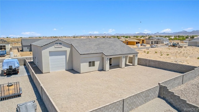 view of front of house with a patio, a mountain view, a tile roof, a residential view, and stucco siding