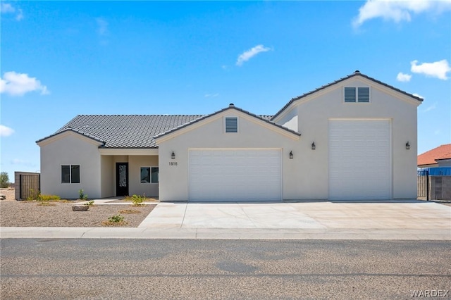 ranch-style house with a garage, fence, a tile roof, concrete driveway, and stucco siding