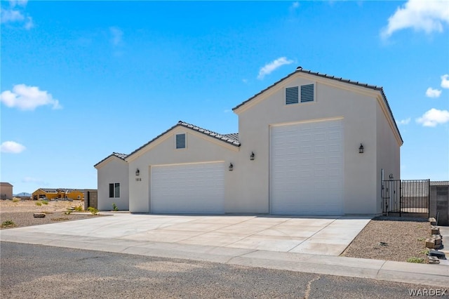 view of front of home featuring driveway, an attached garage, fence, and stucco siding