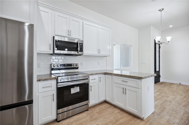 kitchen with stainless steel appliances, light stone counters, white cabinetry, and decorative light fixtures