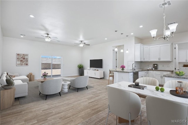 living area with light wood-style floors, ceiling fan with notable chandelier, visible vents, and recessed lighting