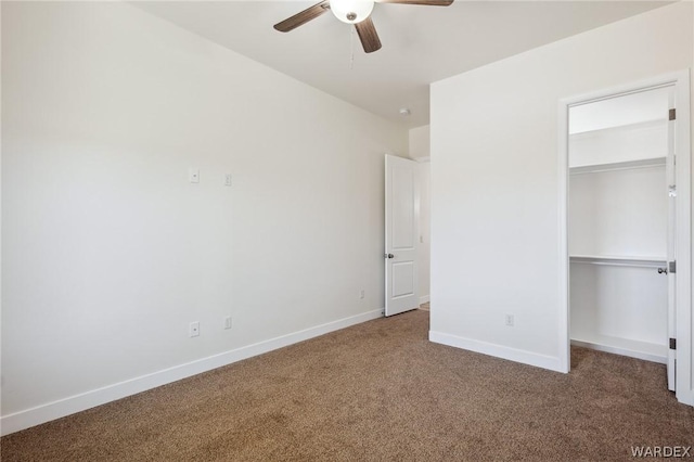 unfurnished bedroom featuring carpet, a closet, a spacious closet, a ceiling fan, and baseboards